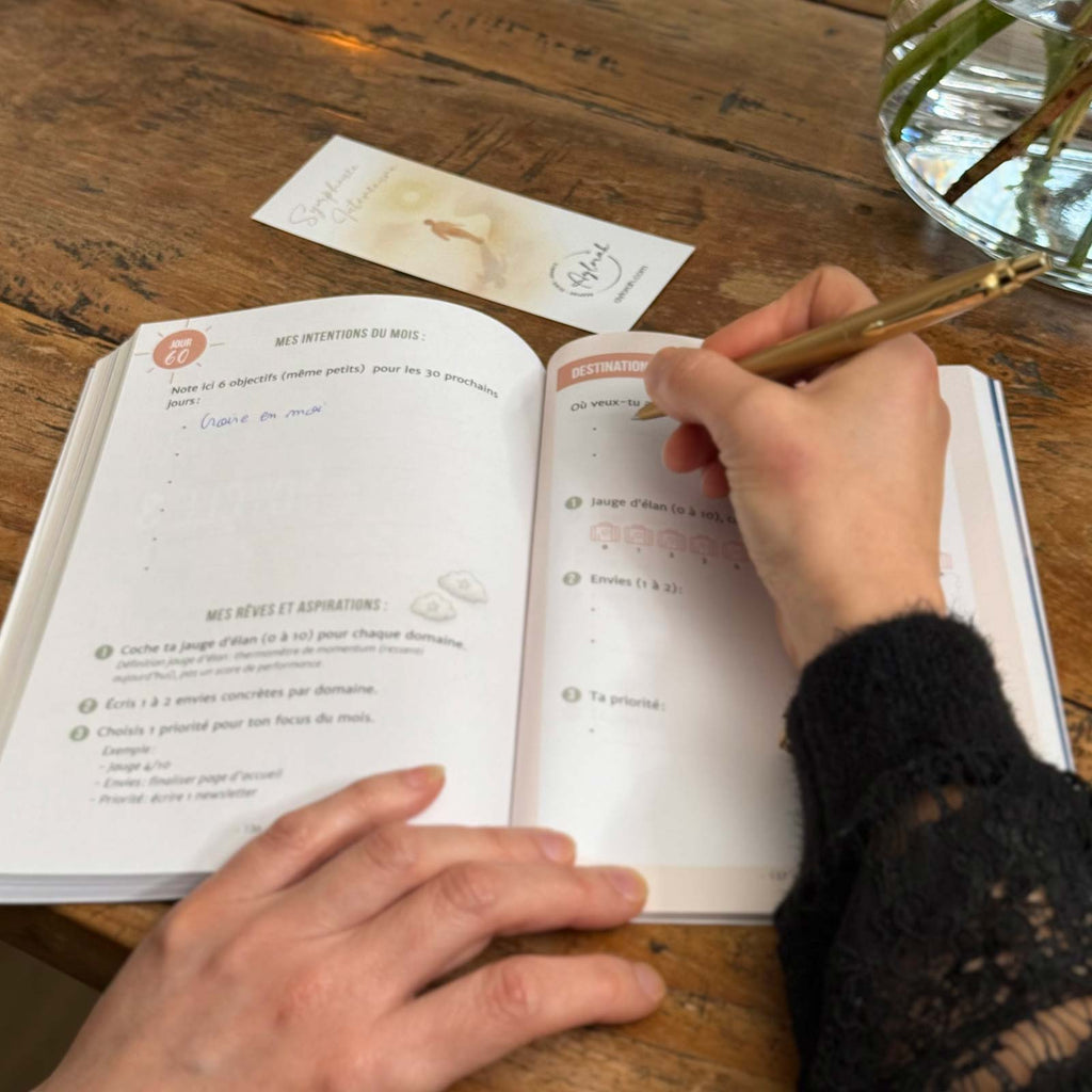 Carnet + marque-page sur table, personne qui écrit dans le carnet, lifestyle ambiance douce