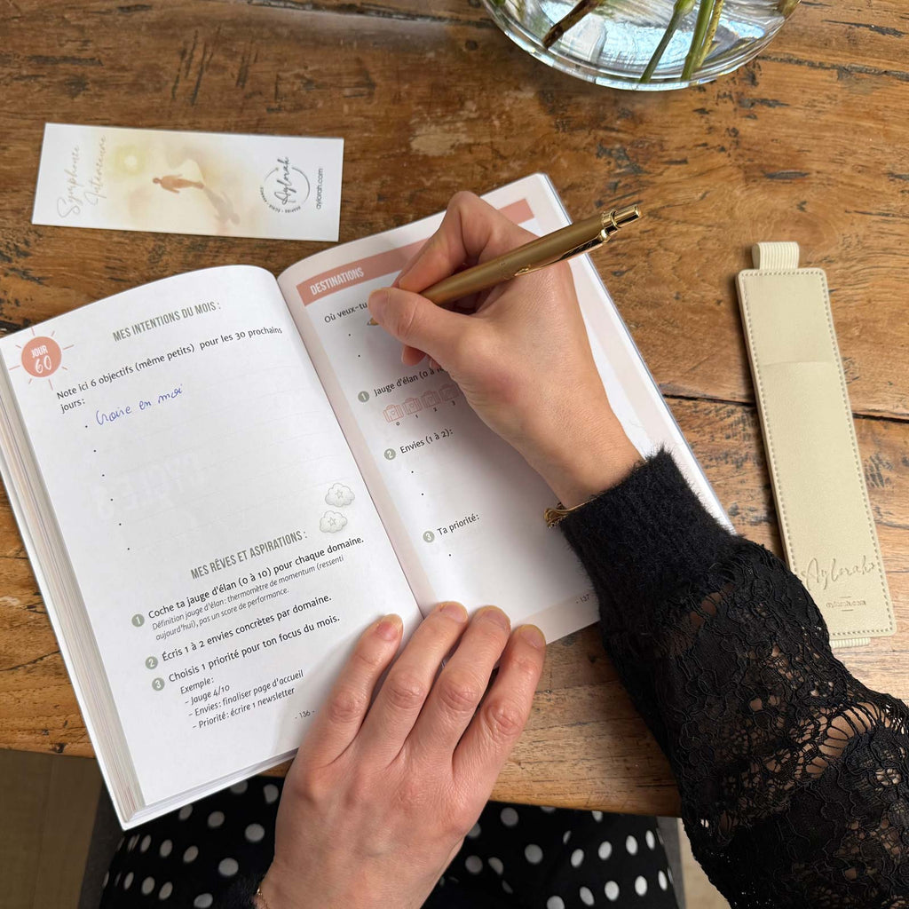 Utilisation du Rituel Nomade, écriture dans le carnet avec porte-stylo à côté.