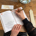 Rituel Signature Aylorah – écriture dans le carnet avec le porte-stylo et le marque-page