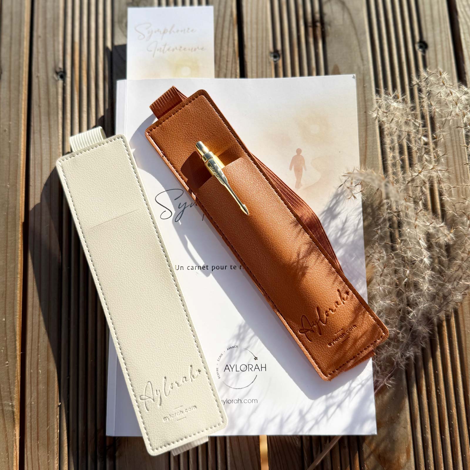 Rituel Signature Aylorah – carnet 90 jours avec porte-stylo camel et beige,  marque-page posés sur une table en bois